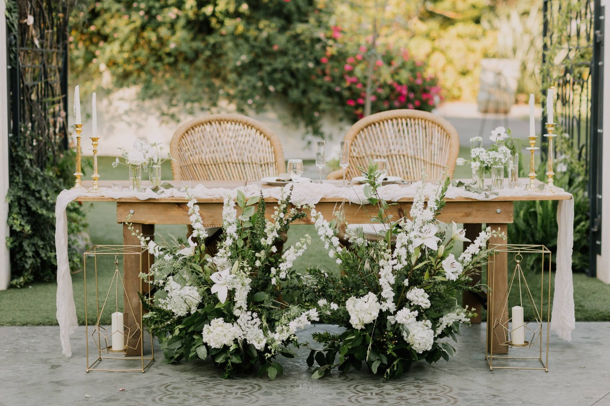 white floral arrangements for sweetheart table with peacock chairs