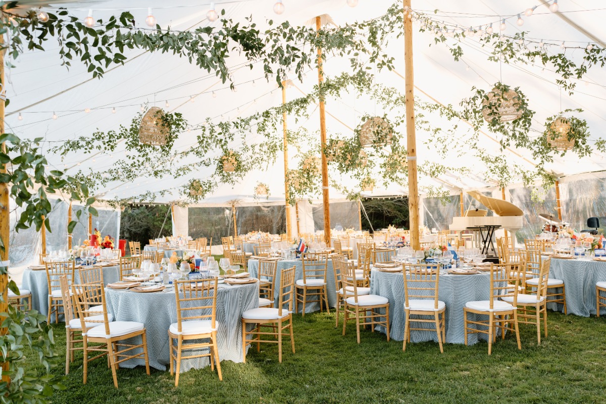 blue and white tented wedding reception with vines